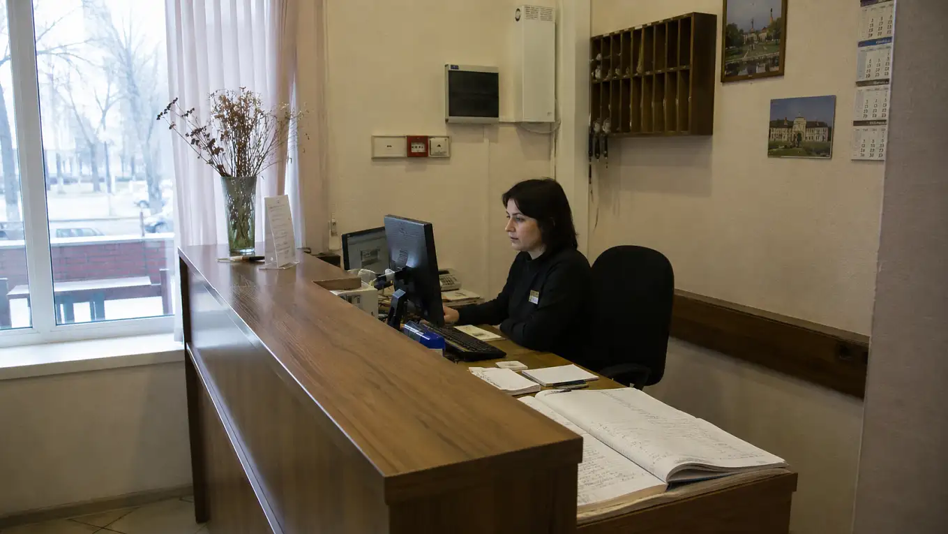 Сотрудник небольшого отеля работает с терминалом регистрации гостей