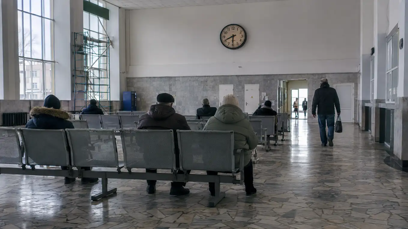 Часы и пассажиры в обычном зале ожидания транспортного терминала.